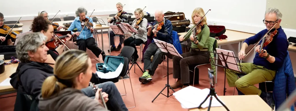 Ten fiddle players seated in a circle playing a traditional song